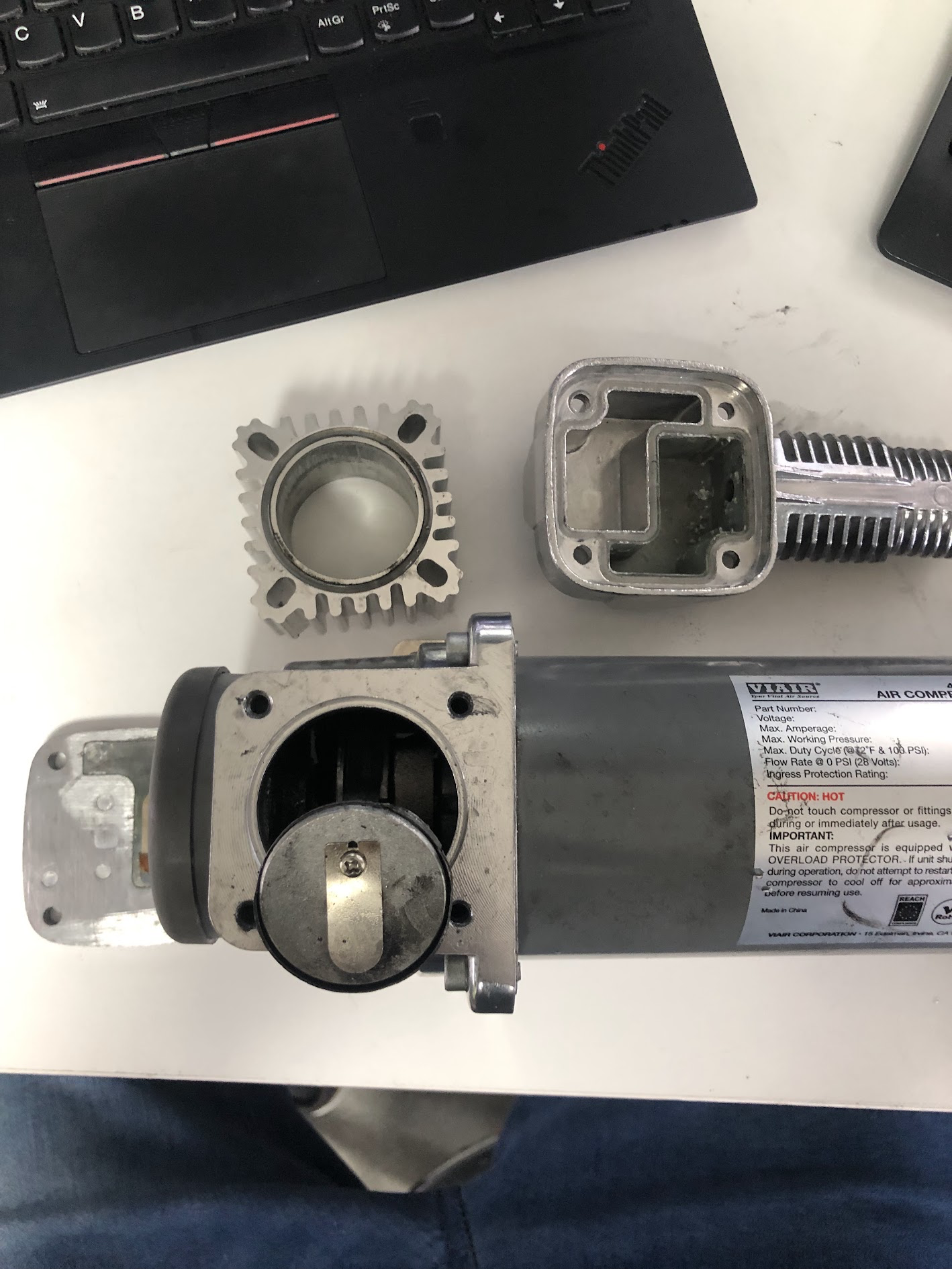 Dismantled air compressor with its cylinder and head laid out on a workbench