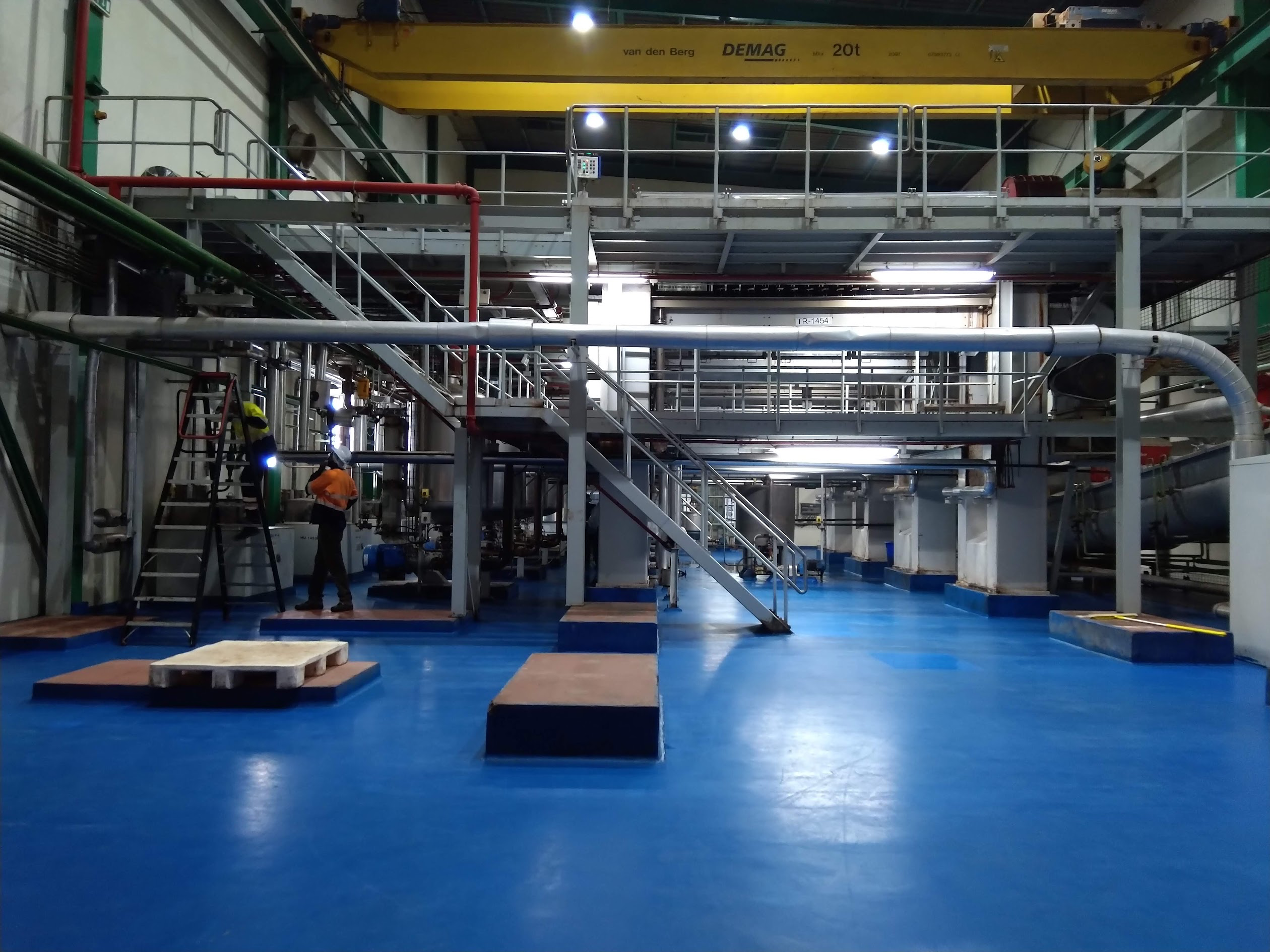 Industrial plant interior with pipework, service platforms and overhead crane